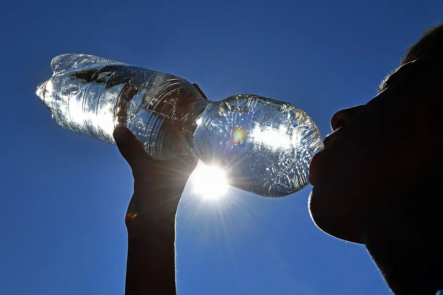 Verheerende Hitzewelle in Deutschland hatte schon über 5000 Todesfälle zur Folge Dunkle Silhouette eines jungen Menschen, der Wasser aus einer Plastikflasche bei großer Hitze im Sommer trinkt.