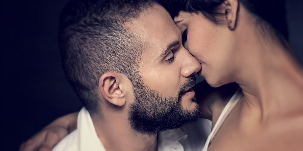 Closeup portrait of gentle loving couple kissing isolated on black background, enjoying romantic relationship, affection and tenderness concept