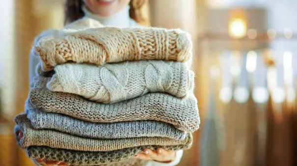 Frau mit Wollpullovern in der Hand - Foto: iStock / CentralITAlliance