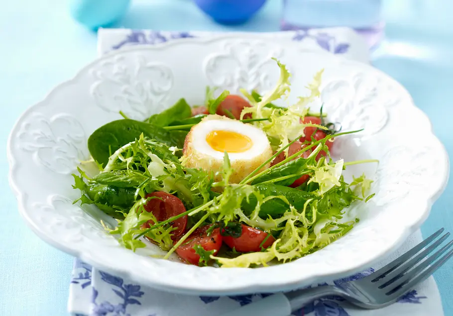Wachsweiche Eier im Kokoszwieback-Mantel Wachsweiche Eier im Kokoszwieback-Mantel auf buntem Salat mit halbierten Kirschtomaten.