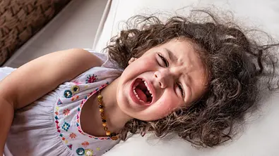 Mädchen liegt auf dem Bett und schreit. - Foto: iStock/mofles