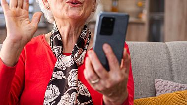 Unerkennbare pensionierte Seniorin nimmt mit ihrem Smartphone im Wohnzimmer ein Video auf. - Foto: Viktorcvetkovic/iStock