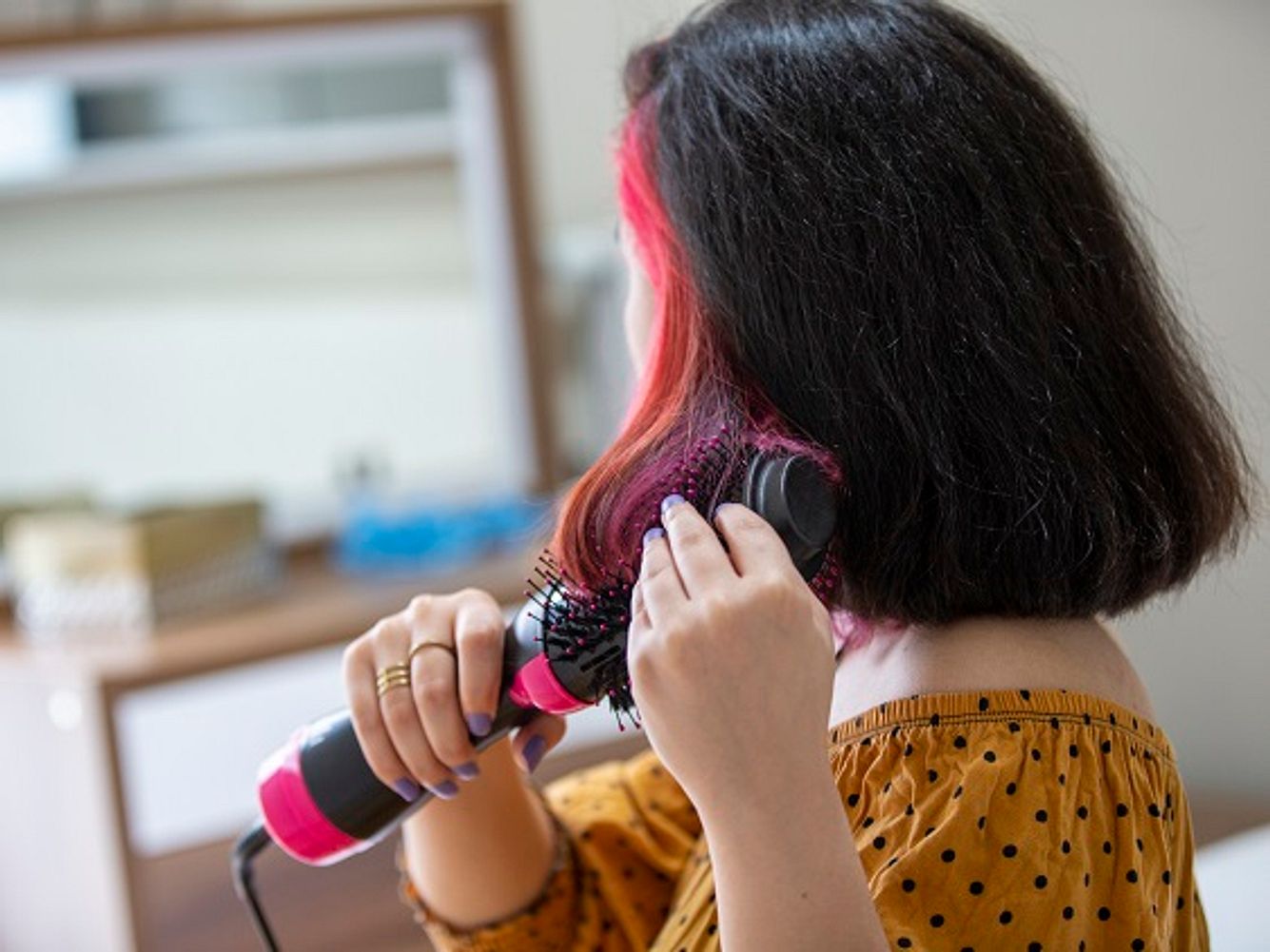 Frau stylt Haare mit Warmluftbürste