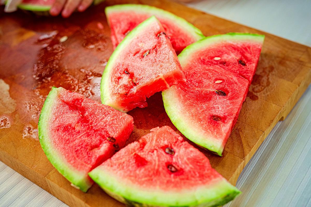 In Dreiecke aufgeschnittene Wassermelonenspalten auf einem Holzbrett.