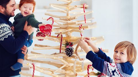 Weihnachtsbaum aus Holz - die Familie schmückt ihn - Foto: iStock/olesiabilkei