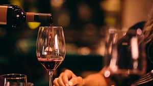 Nahaufnahme Rotwein servieren, Frau sitzt am Esstisch. - Foto: wundervisuals/iStock