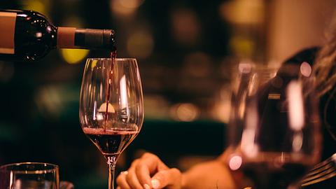 Nahaufnahme Rotwein servieren, Frau sitzt am Esstisch. - Foto: wundervisuals/iStock