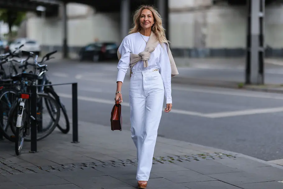 Weiße Wide Leg-Jeans stylen Lange weiße Jeans mit weitem Bein kombiniert zu einem weißen Longsleeve und beige-braunen Accessoires.