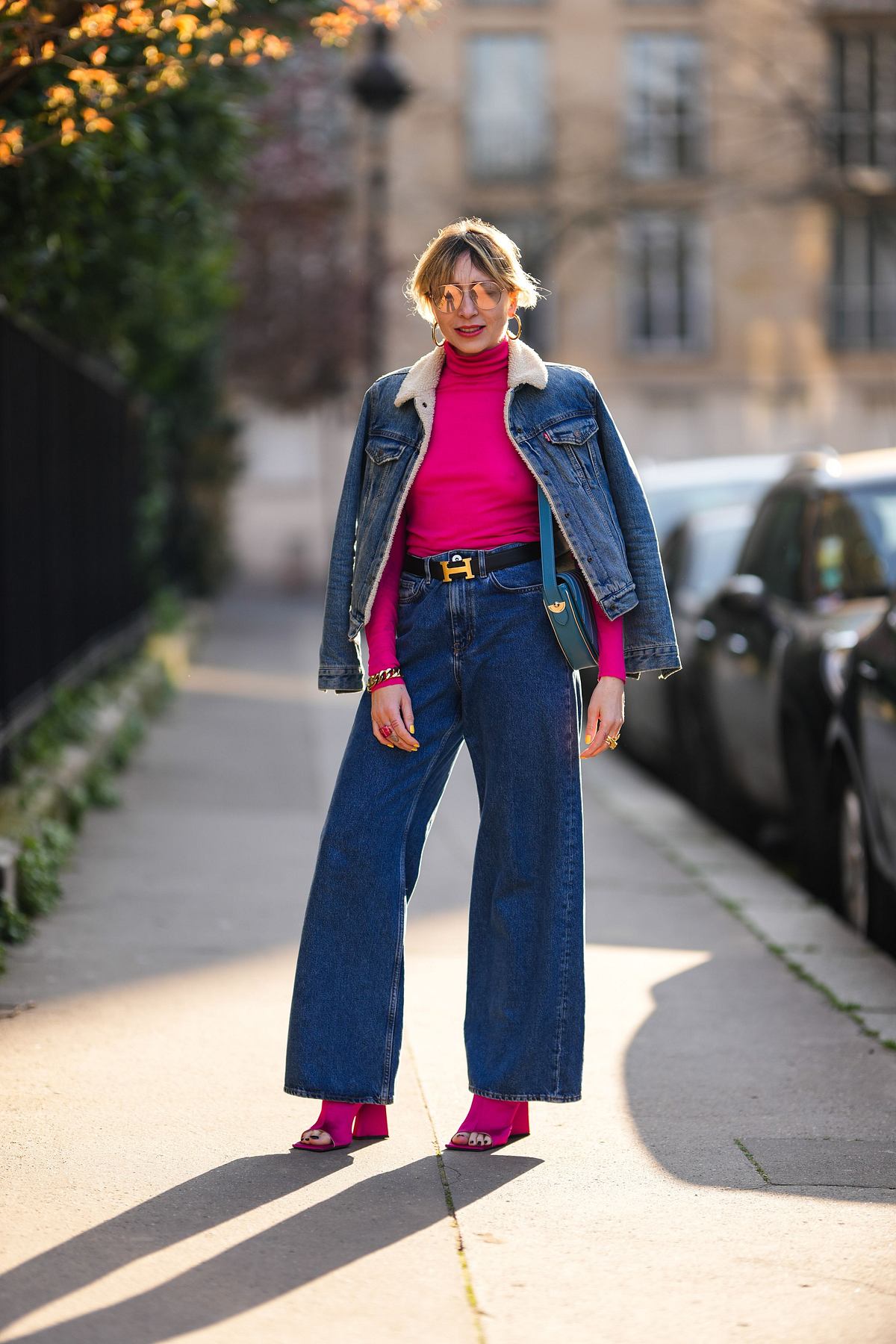 Eine Frau trägt eine Jeans, eine passende Jeansjacke, ein rotes Oberteil und rote Schuhe.