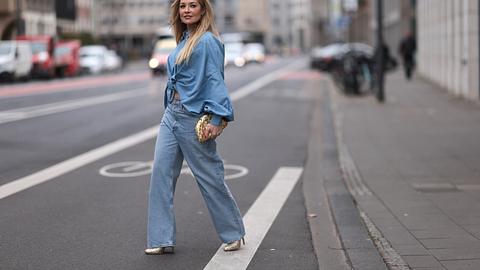 Eine Frau trägt eine weite Jeans mit einem blauen Oberteil und läuft über eine Straße. - Foto: Jeremy Moeller/Getty Images