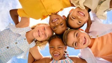 Ein Gruppe von Kindern beugt sich über die Kamera und lacht - Foto: iStock/monkeybusinessimages