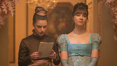 Haycinth liest das Klatschblatt Lady Whistledown und Eloise steht neben ihr. - Foto: Liam Daniel / Netflix