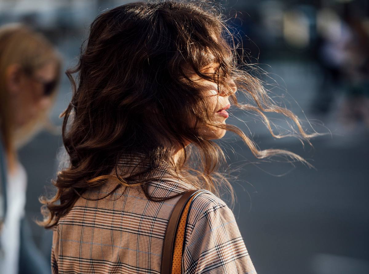 Frau mit braunen langen Haaren im Wind (Themenbild) 