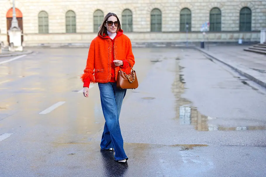 Eine Frau läuft eine Straße entlang und trägt ein rotes Oberteil zu ihrer weiten jeans. 