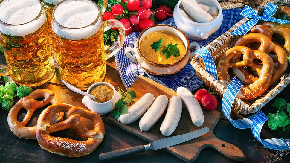 Oktoberfest-Spezialitäten auf einem Holztisch: Bier, Brezeln, Weißwurst, Obatzda - Foto: alexraths / iStock