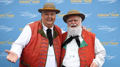 Wolfgang Schwalm und Wilfried Gliem posieren gemeinsam in traditionellen roten Westen und Hüten vor einer Eventwand - Foto: IMAGO / Zoonar
