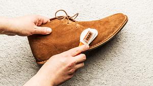 Mann putzt Wildleder-Schuhe mit einer Bürste (Themenbild) - Foto: Cleardesign1/iStock