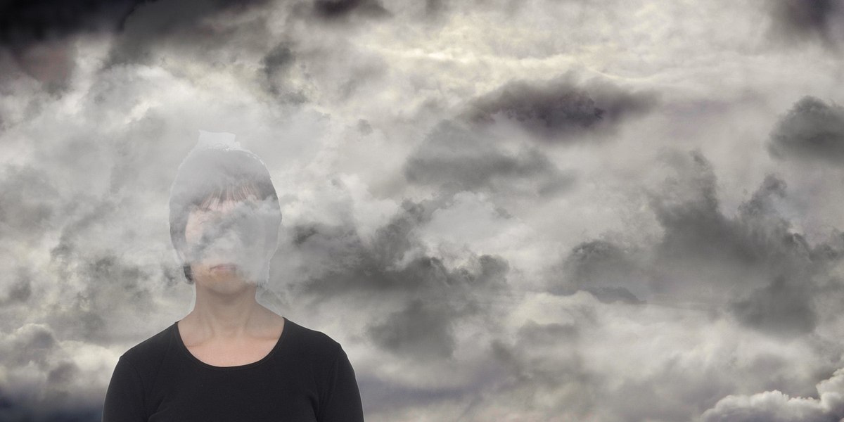 Frau mit grauen Wolken. Depression, Traurigkeit (Themenbild)