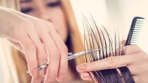 Frau schneidet die Haare einer anderen Person.  - Foto: MilanMarkovic/iStock (Themenbild)