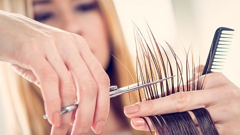 Frau schneidet die Haare einer anderen Person.  - Foto: MilanMarkovic/iStock (Themenbild)